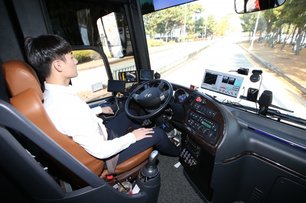 KT 자율주행 버스를 탑승한 KT 직원이 양손을 놓고 차량으로 전달되는 신호를 확인하고 있다.
