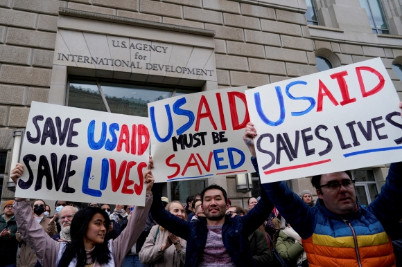 미국 워싱턴DC에 위치한 국제개발처(USAID) 건물 앞에서 직원들이 플래카드를 들고 항의하는 모습 (출처 : 로이터 연합뉴스)