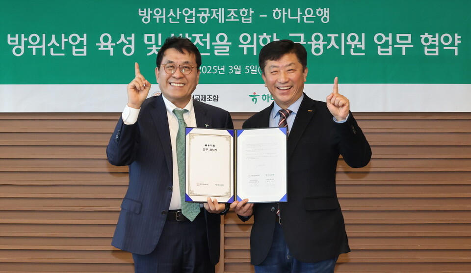 하나은행은 5일 방위산업공제조합과 K-방위산업의 육성 및 금융 지원을 위한 업무협약을 체결했다. 이날 협약식에 참석한 김진우 하나은행 중앙영업그룹 부행장(사진 왼쪽)이 김희철 방위산업공제조합 상근부이사장(사진 오른쪽)과 협약서를 들고 기념촬영을 하고 있다.